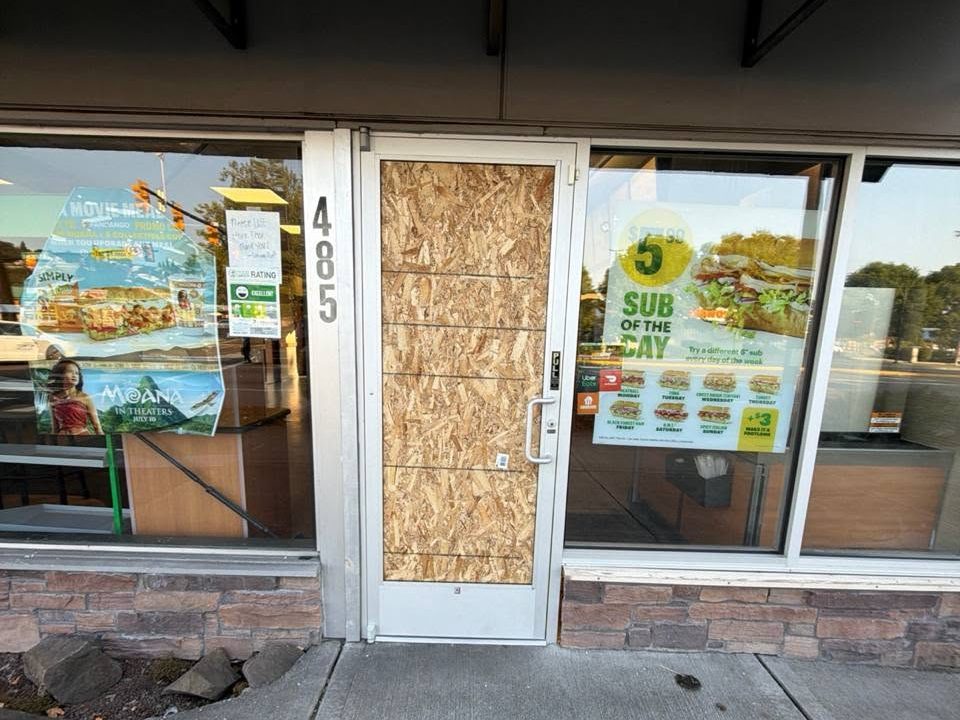 Storefront door boarded up with plywood after a break-in
